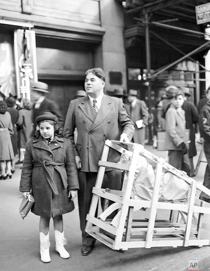 A Christmas Eve shopper with his daughter and a crated rocking horse tries to hail a cab outside Macy’s, December 24, 1946. - Rare Vintage Photos