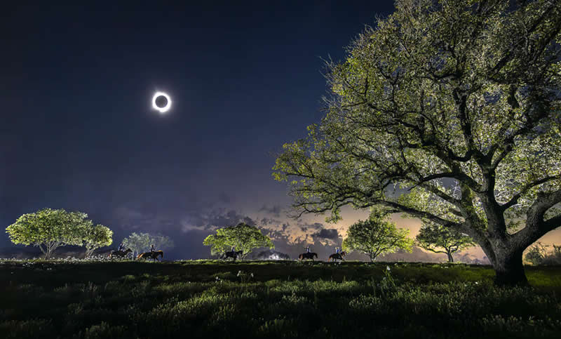 2026 Memorial Maria Luisa Awards: Best Mountain & Nature Photos Revealed 59 Horse riders moving across a landscape at night under a solar eclipse, with trees illuminated and a glowing sky in the background.