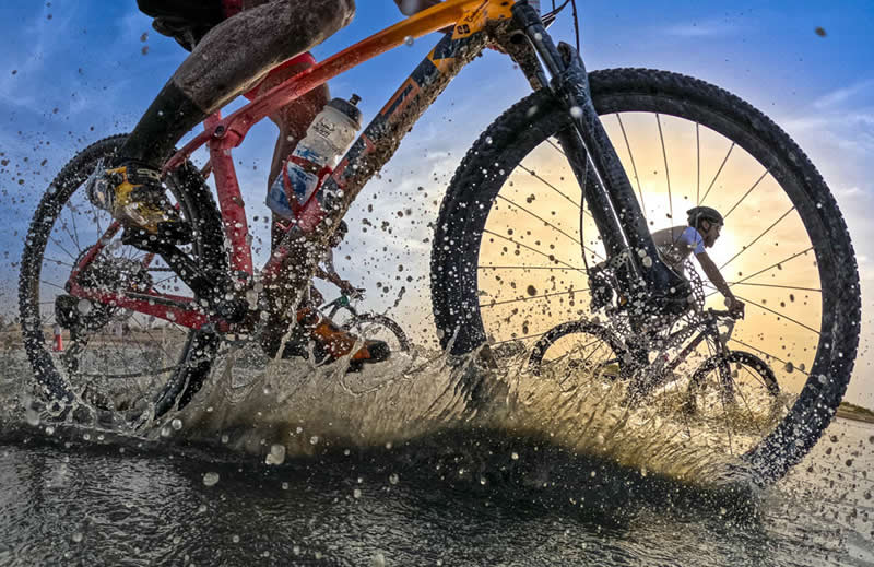 2026 Memorial Maria Luisa Awards: Best Mountain & Nature Photos Revealed 44 Close-up of cyclists riding through water and mud, with splashes frozen mid-air and wheels in motion during a race.