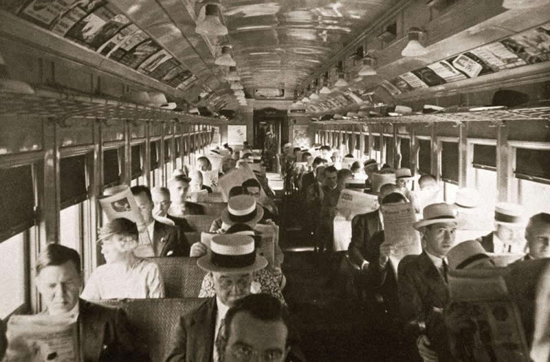 Commuters on a train car in New York City in the 1920s. Look at all the newspapers and hats!