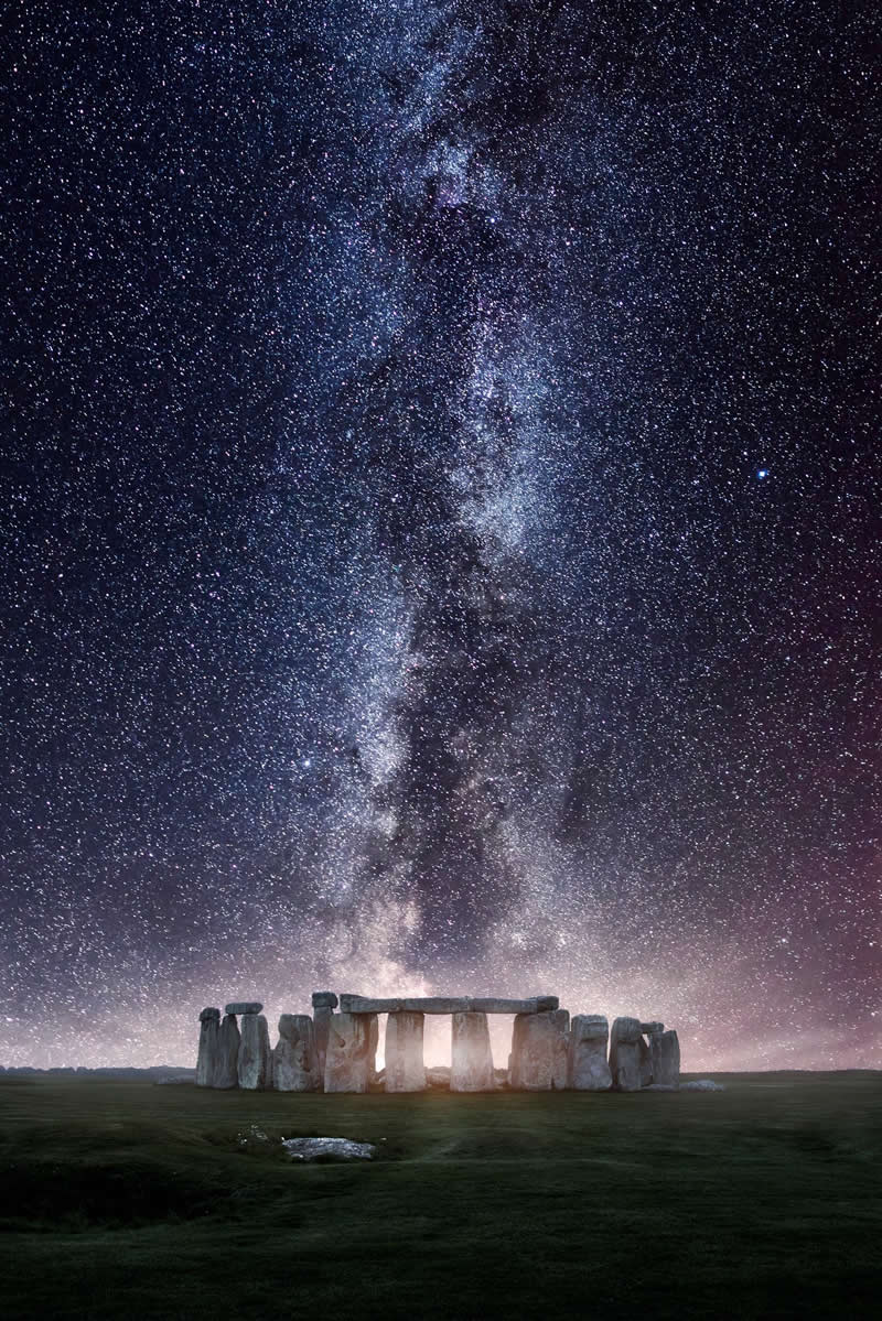 Stonehenge monument under the Milky Way galaxy with thousands of stars forming a bright vertical band above the ancient stone circle.