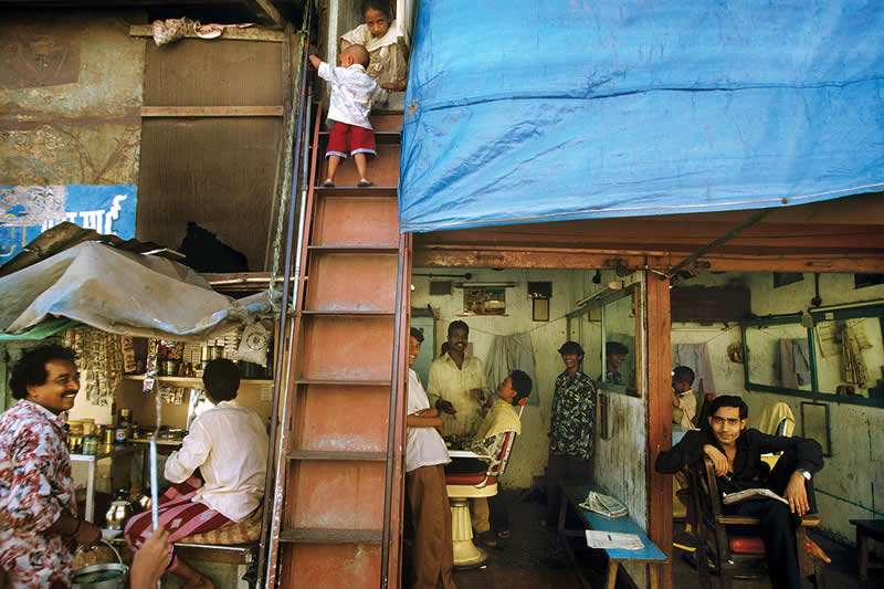 A barber shop and washing hung up to dry in Fishermen's Colony, Mumbai by Raghu Rai - Iconic Color Photos by Legendary Photographers