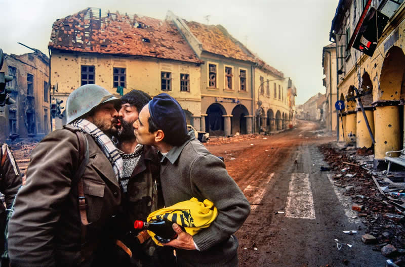 People - Bronze Winner: Kiss in the Ruins - Vukovar 1991 by Dragoljub Zamurović - 1839 Awards Color Photography Contest 2026 Winners