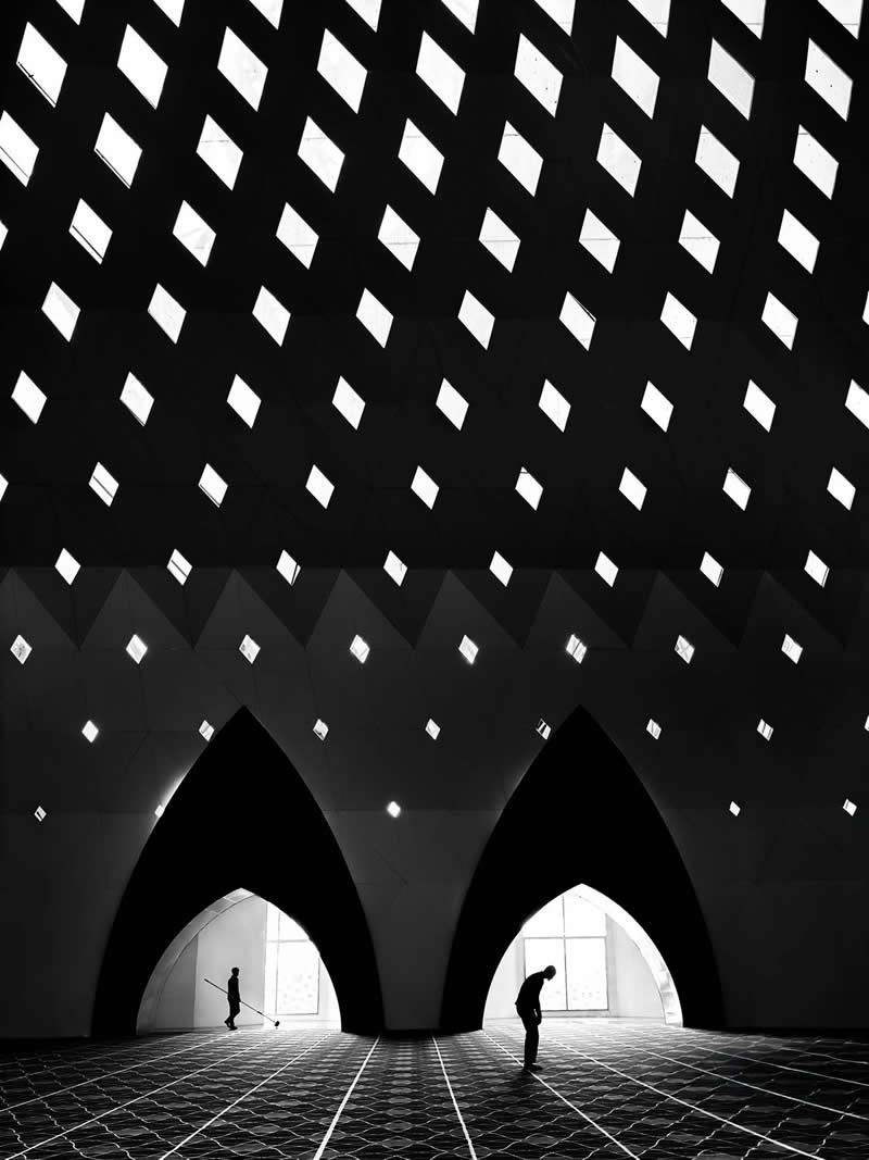 The Mobile Revolution: What the Winners of 35AWARDS Tell Us About the Future of Phone Cameras 30 Black-and-white architectural interior featuring large pointed arches, a ceiling patterned with diamond-shaped openings, and two silhouetted people standing beneath. Strong geometric lines, dramatic contrasts, and repeating shapes create depth, symmetry, and a striking minimalist visual effect.
