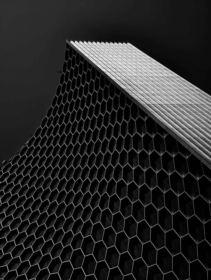 The Mobile Revolution: What the Winners of 35AWARDS Tell Us About the Future of Phone Cameras 41 A dramatic low-angle view of a modern high-rise building featuring a repeating honeycomb-patterned facade. The geometric design rises toward a dark sky, emphasizing scale, symmetry, texture, and architectural elegance through strong contrast and striking perspective.
