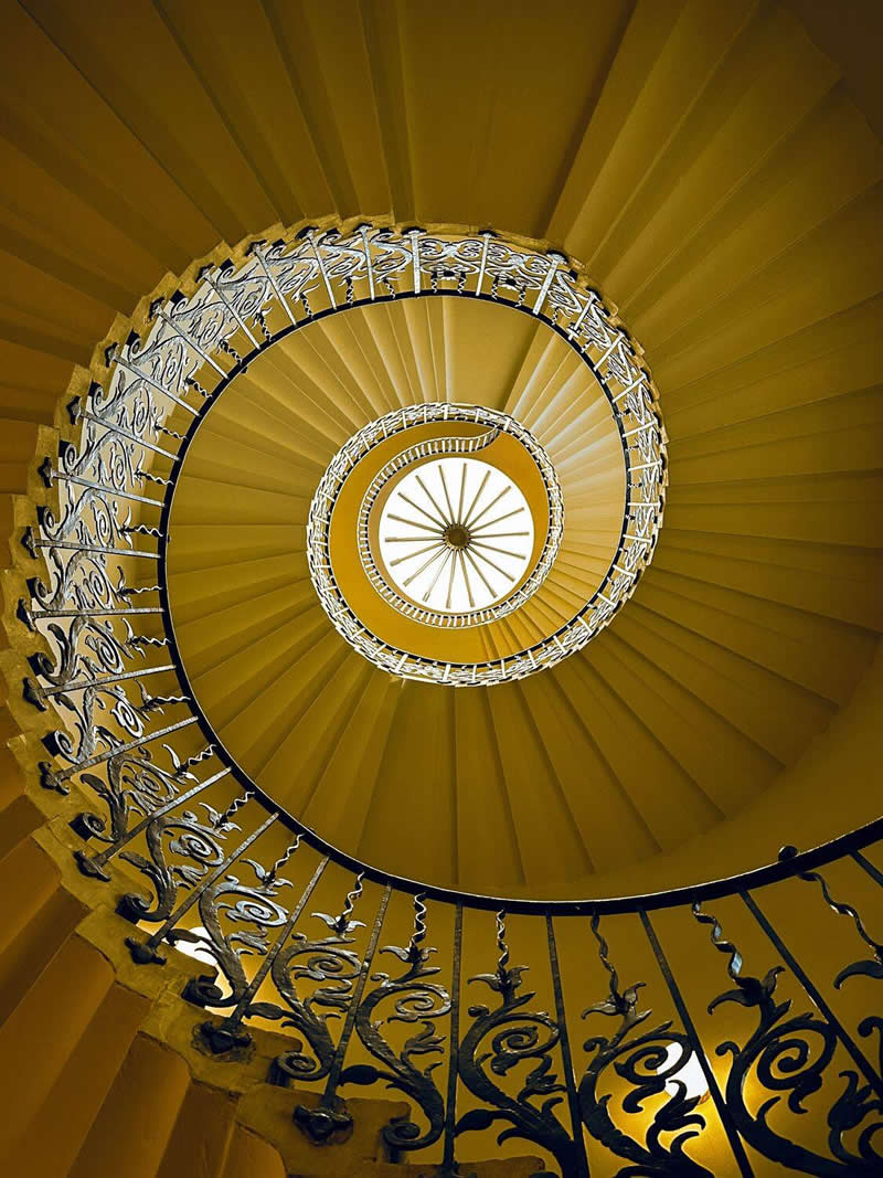 The Mobile Revolution: What the Winners of 35AWARDS Tell Us About the Future of Phone Cameras 46 An upward view of a grand spiral staircase with ornate wrought-iron railings and warm golden tones. The steps curve inward toward a bright circular center, creating striking symmetry, depth, and a captivating geometric pattern that emphasizes architectural beauty.
