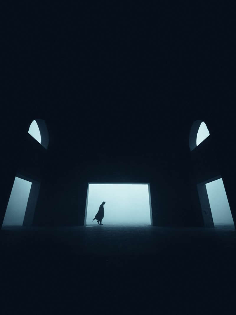 The Mobile Revolution: What the Winners of 35AWARDS Tell Us About the Future of Phone Cameras 35 A lone silhouetted figure walks through a dark architectural space toward a bright, fog-filled opening. Symmetrical archways and strong contrast between shadow and light create a minimalist, moody scene with a sense of mystery, scale, and solitude.