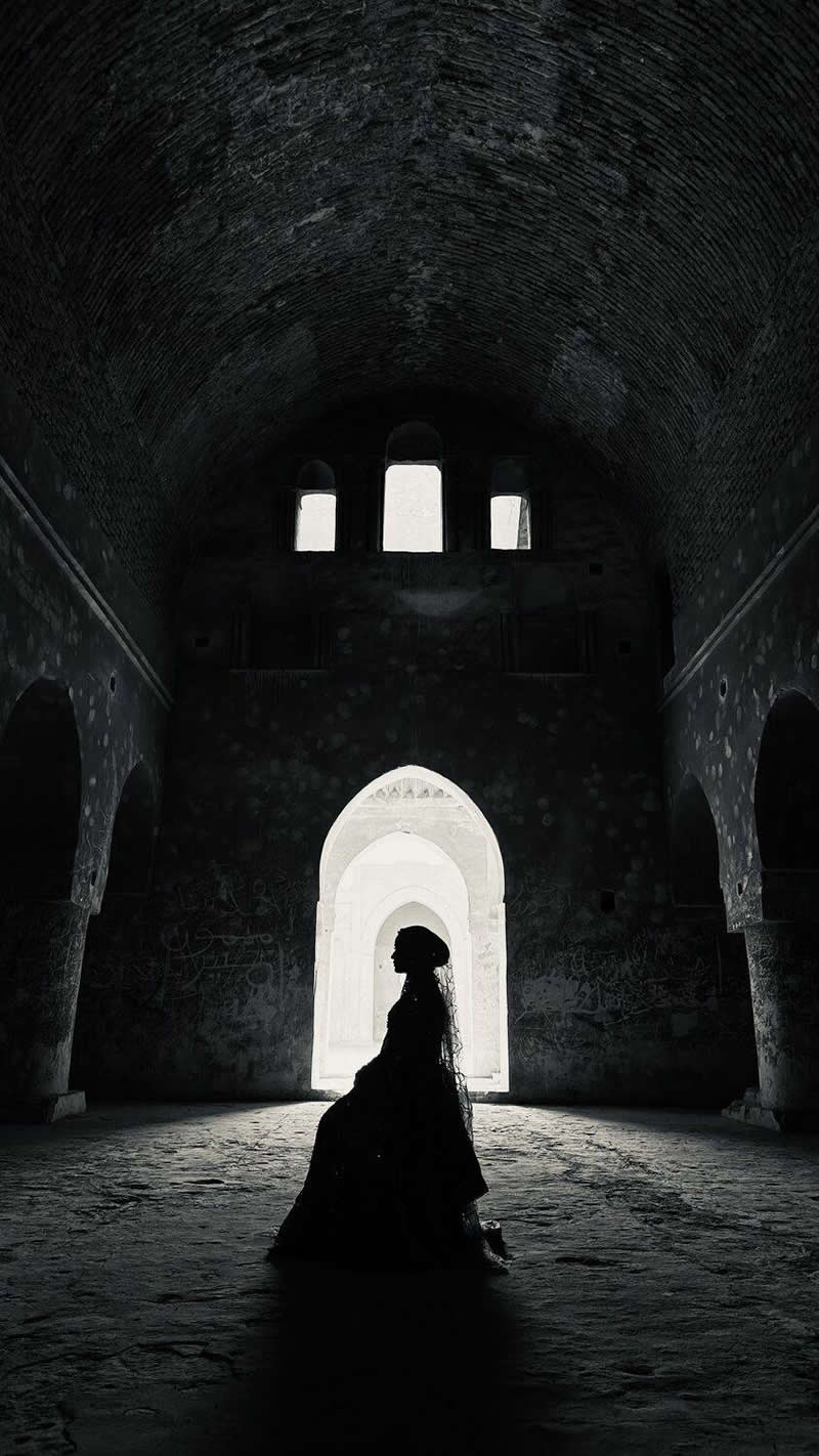 The Mobile Revolution: What the Winners of 35AWARDS Tell Us About the Future of Phone Cameras 36 A silhouetted figure in a long dress sits inside a large historic hall, framed by bright arched doorways. Dramatic contrast between the dark interior and glowing background emphasizes the architecture, symmetry, and the subject’s graceful profile, creating a moody, elegant atmosphere.