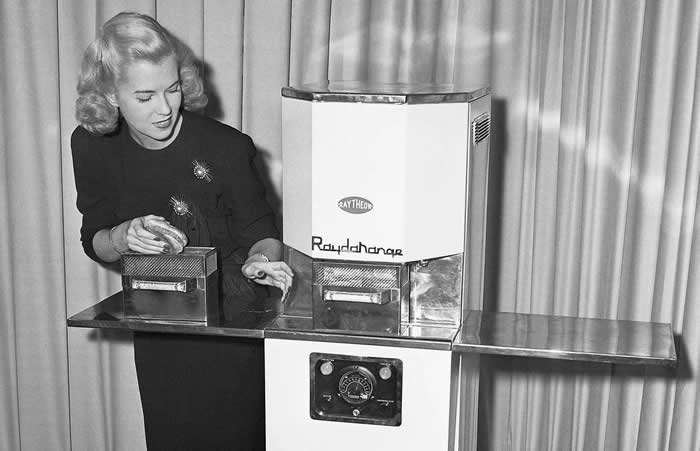 The Past Unfiltered: 36 Rare Historical Photos That Reveal the Human Side of History 67 A woman demonstrating how to use the first commercial microwave oven called the Radarange, 1947. This was made by Raytheon.