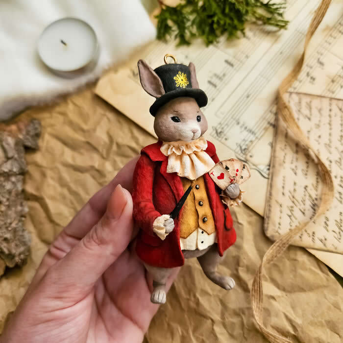 Miniature World: 33 Cotton Wool Sculptures by Katya Celebrating the Magic of Handmade Craft 49 A handcrafted miniature rabbit ornament made from cotton wool wears a red coat, golden waistcoat, ruffled collar, and top hat while holding a tiny heart-themed card and wand against a vintage paper backdrop.