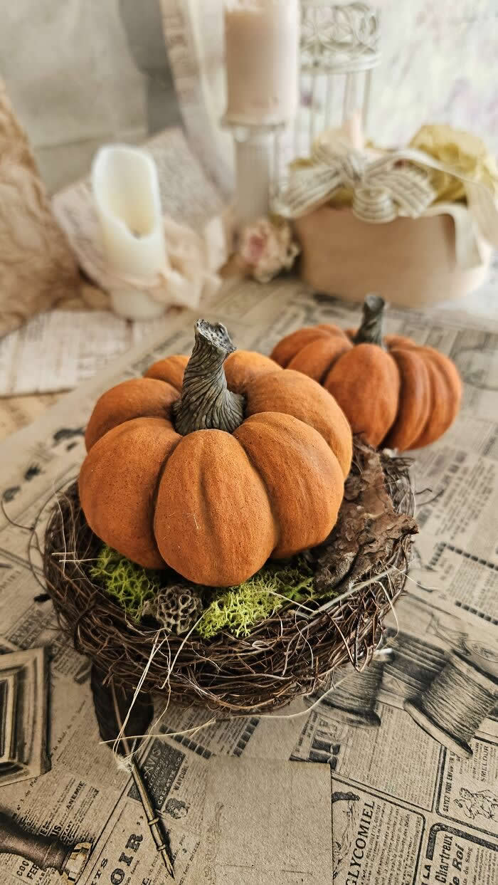 Miniature World: 33 Cotton Wool Sculptures by Katya Celebrating the Magic of Handmade Craft 52 Handcrafted miniature pumpkin ornaments made from cotton wool sit in a rustic twig nest with moss, styled on vintage newspaper pages beside candles and soft autumn décor in a warm, nostalgic setting.
