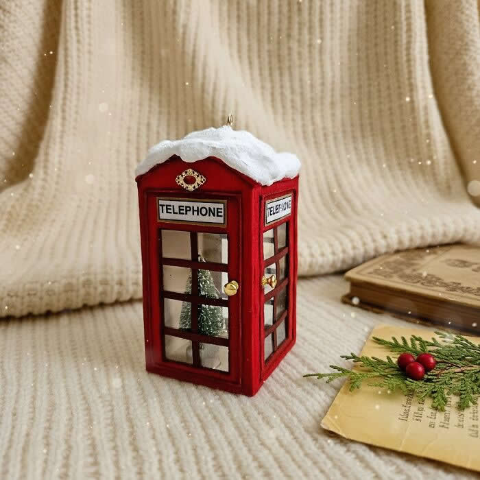 Miniature World: 33 Cotton Wool Sculptures by Katya Celebrating the Magic of Handmade Craft 46 A handcrafted miniature red telephone booth ornament made from cotton wool stands on a cozy knitted backdrop, topped with snow and featuring tiny window details with a small tree visible inside.