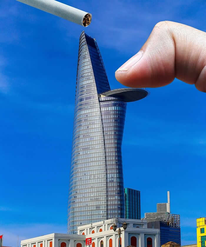Pure Visual Magic: 35 Mind-Bending Forced Perspective Photos by Hugo Suíssas 51 A hand pinches the circular helipad jutting from a tall glass skyscraper while a cigarette hovers above the tower, making it look as if the building is being used like an ashtray in a clever forced perspective illusion.