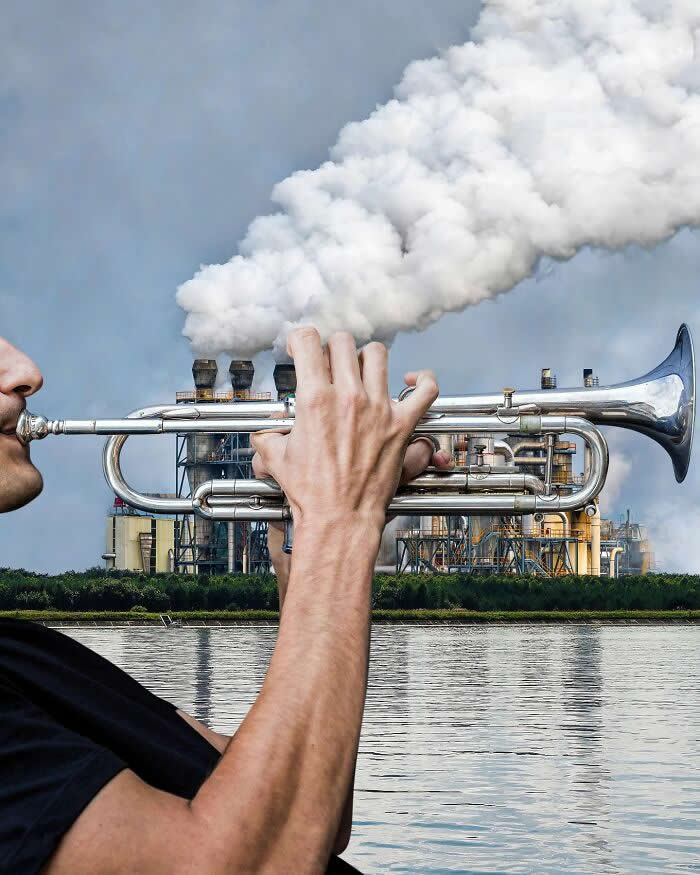 Pure Visual Magic: 35 Mind-Bending Forced Perspective Photos by Hugo Suíssas 58 A man holds a silver trumpet in the foreground, aligned with an industrial plant in the background so the factory’s thick white smoke looks like it’s blasting out of the trumpet in a playful forced perspective illusion.