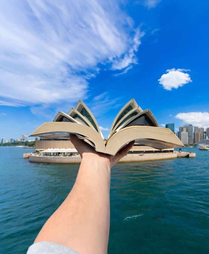 Pure Visual Magic: 35 Mind-Bending Forced Perspective Photos by Hugo Suíssas 60 A hand holds an open book in the foreground, perfectly aligned with the Sydney Opera House so the building’s iconic sail-like roofs appear to rise from the book’s pages in a playful forced perspective illusion.