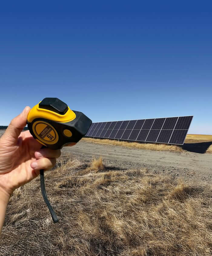 Pure Visual Magic: 35 Mind-Bending Forced Perspective Photos by Hugo Suíssas 62 A hand holds a yellow tape measure in the foreground, aligned with a long row of solar panels in a dry open field so the panels appear to extend directly from the measuring tape in a playful forced perspective illusion.